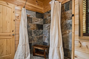 Step into your rustic retreat natural stone tile, warm wood walls, and soft linen curtains create a tranquil shower sanctuary.