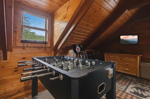 Challenge your crew to a friendly foosball match in this cozy loft game space, where woodpaneled walls and mountain charm create the perfect retreat for playful competition and relaxation.