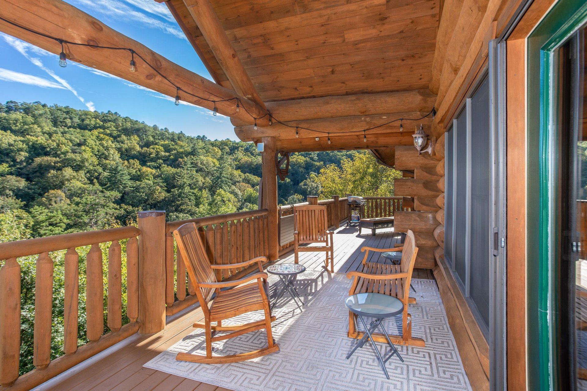 Outdoor seating with string lighting on the covered deck at Great View Lodge, a 5bedroom cabin rental located in Pigeon Forge
