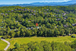 Aerial view of the property nestled in a lush, forested neighborhood with rolling hills and stunning mountain ranges stretching across the horizon.