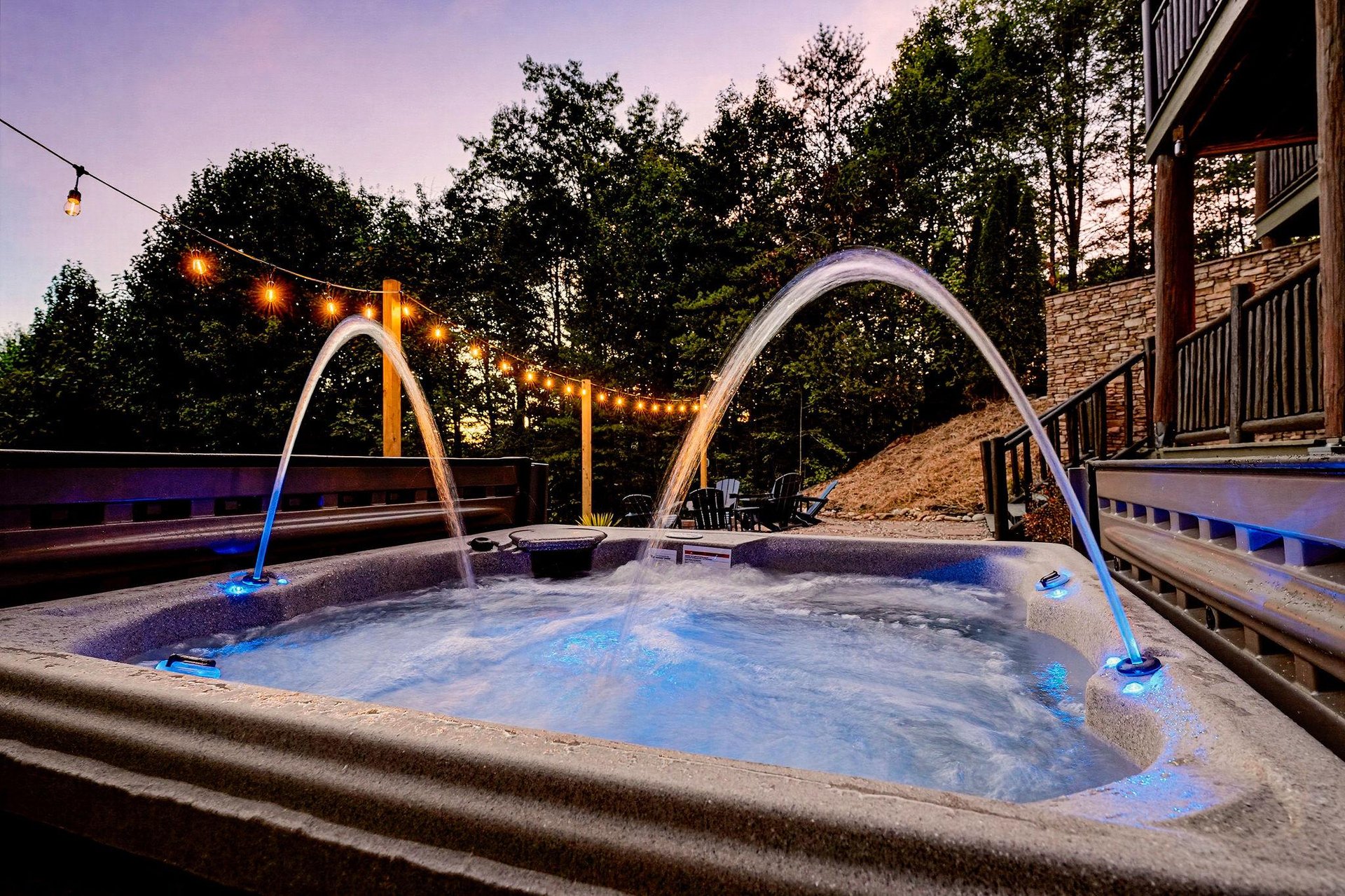 Soak under the stars in your private hot tub with water arcs and string lights creating a magical evening ambiance.