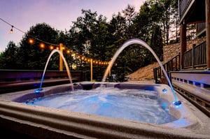 Soak under the stars in your private hot tub with water arcs and string lights creating a magical evening ambiance.