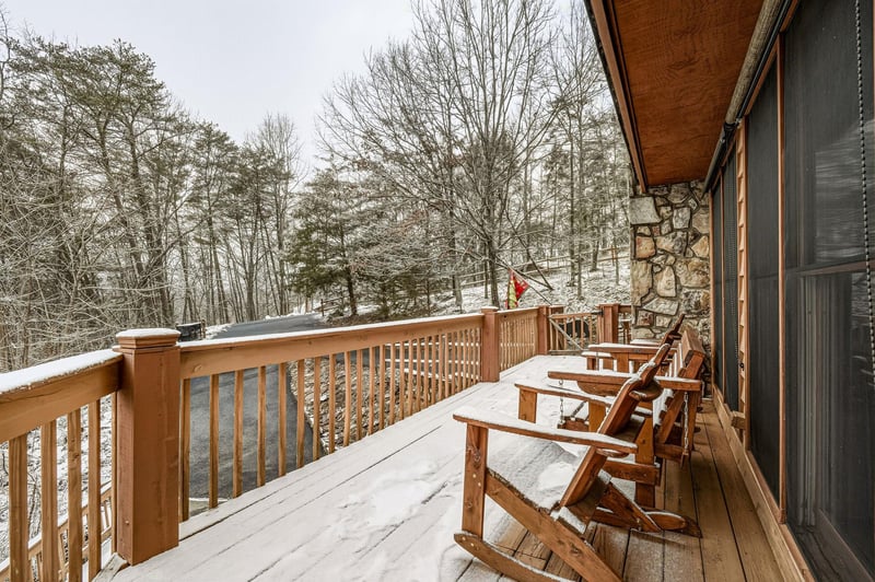 Cozy up on this snowkissed deck with rustic chairs overlooking a serene winter forest, perfect for your morning coffee.