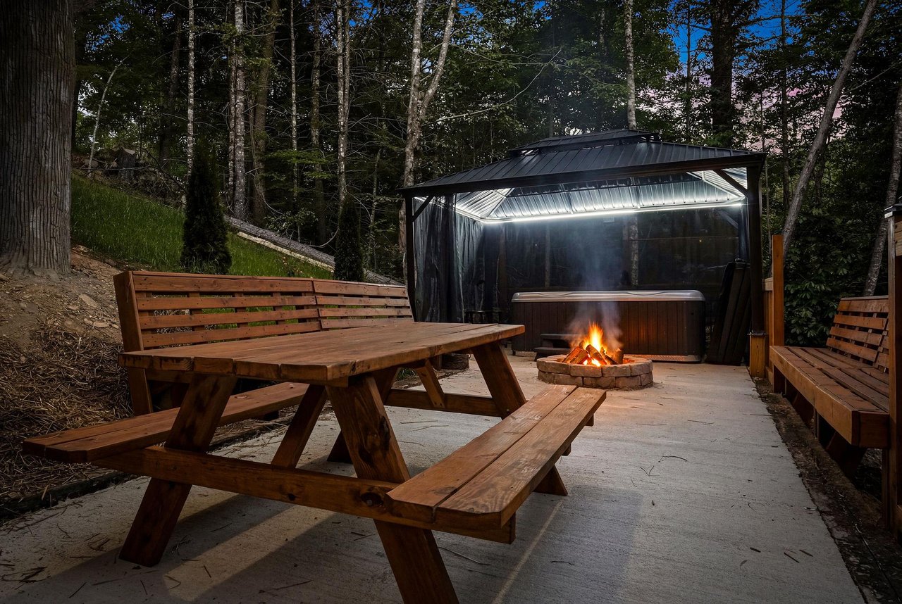 A private outdoor retreat nestled in the woods where you can unwind by the fire pit, soak in the sheltered hot tub, and enjoy peaceful evenings under the trees.