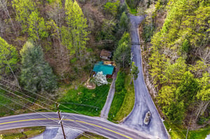 Aerial view of a charming property nestled among vibrant spring foliage, showcasing the peaceful rural setting and easy road access.