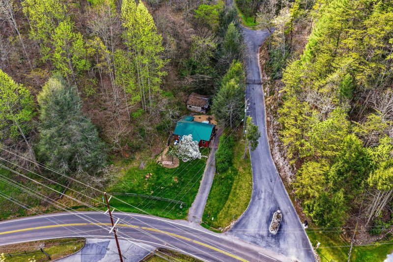 Aerial view of a charming property nestled among vibrant spring foliage, showcasing the peaceful rural setting and easy road access.