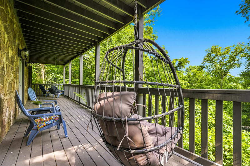 Relax in the hammock chair on your private deck, surrounded by lush tree canopy and summer sky—your peaceful escape awaits.