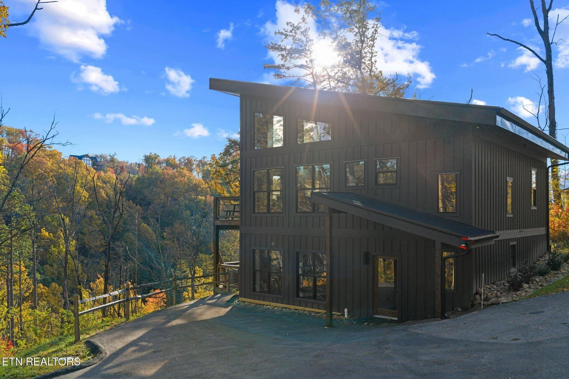 Modern mountain retreat nestled in vibrant autumn foliage with expansive windows capturing natural beauty and hillside vistas.