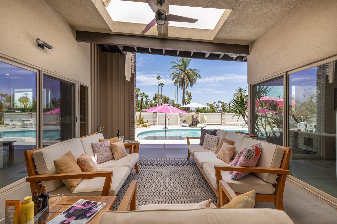 Covered patio just off of the living and dining space with outdoor seating, outdoor fan, and views of both the poolspa and golf course.
