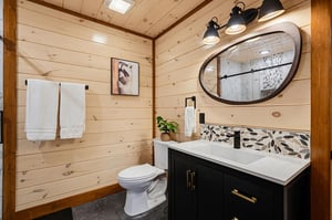 Step into a beautifully designed bathroom featuring warm shiplap walls, elegant pebble tile accents, and modern fixtures. Fresh towels await your arrival in this inviting, spalike space.