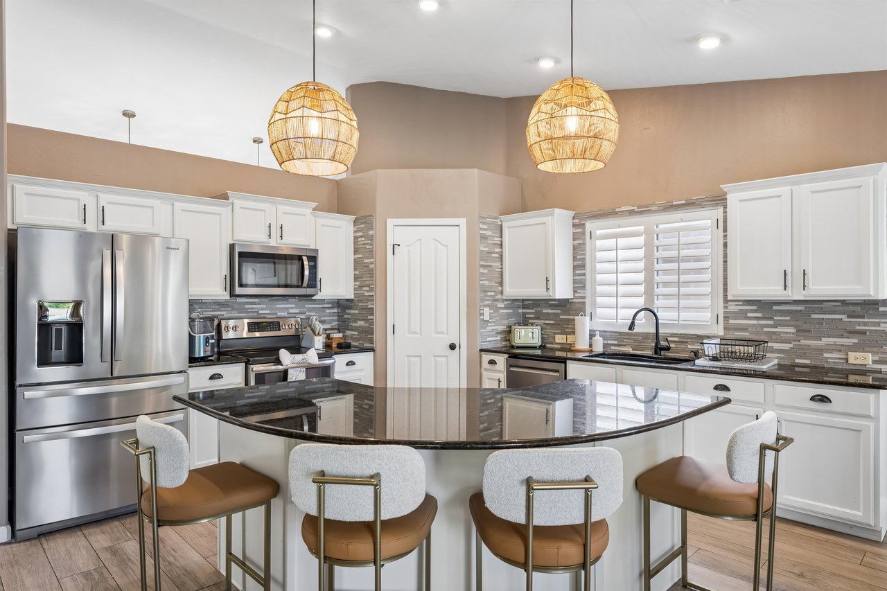 Stainless steel appliances, island counter with seating for 4, and cooking essentials.