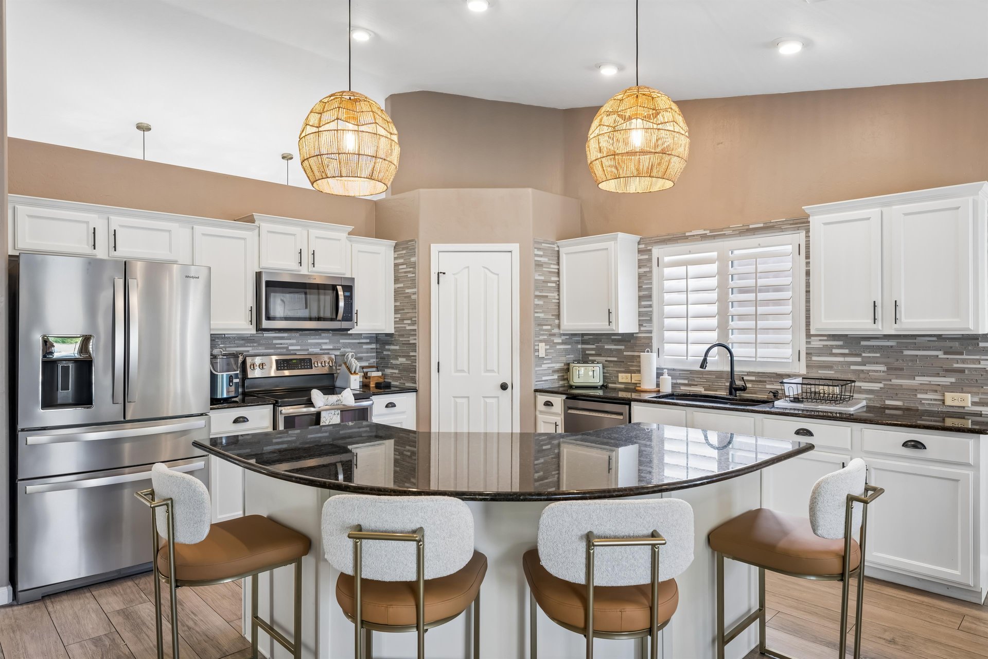 Stainless steel appliances, island counter with seating for 4, and cooking essentials.