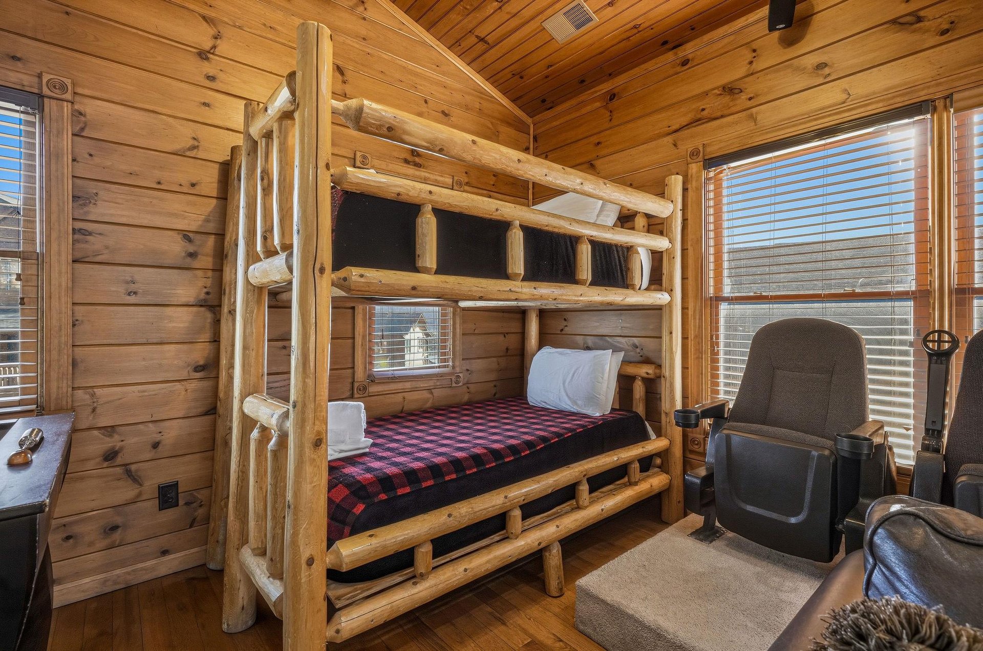 Rustic log bunk bed brings cozy cabin charm to your stay, with warm wood walls and soft natural light inviting restful nights.
