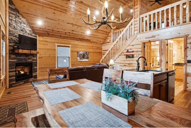 Gather around this rustic dining table while the fireplace crackles nearby. Your mountain retreat features a chandelier overhead and open kitchen.