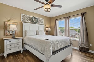Sink into the plush bedding and let the ceiling fan gently cool you as sunlight streams through the windows—your peaceful retreat awaits.