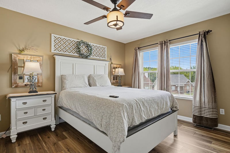 Sink into the plush bedding and let the ceiling fan gently cool you as sunlight streams through the windows—your peaceful retreat awaits.