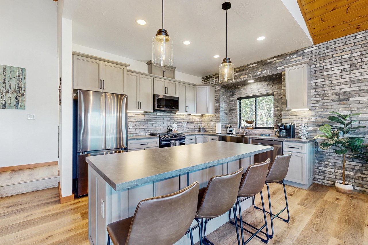Stainless steel appliances, cooking essentials, kitchen island, and counter seating for 4 guests.