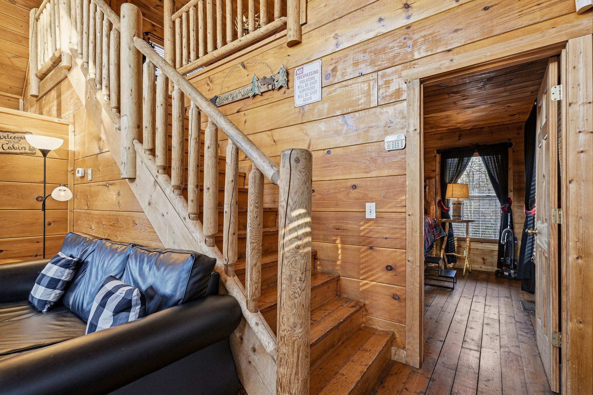 Step into your cozy cabin retreat with rustic log stairs, leather seating, and warm wood surroundings that invite relaxation.
