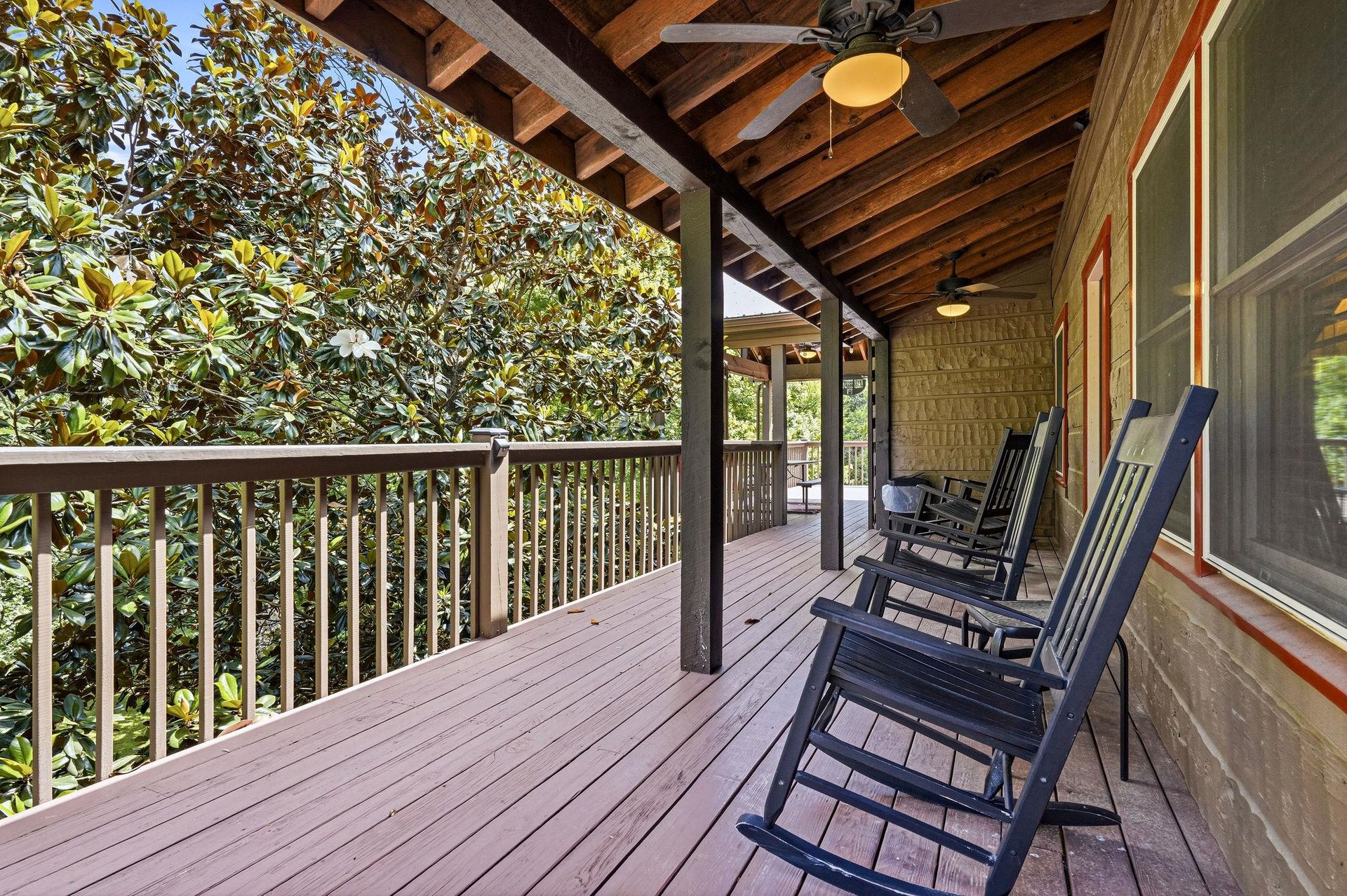 Unwind in classic rocking chairs on your private deck, surrounded by lush greenery and peaceful natural beauty perfect for morning coffee or sunset relaxation.