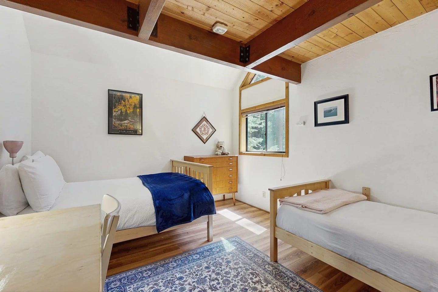 Located on the main floor, the third bedroom offers flexible sleeping with a queen bed and a twin bed, plus a dedicated workspace and dresser — a great fit for families or groups needing extra space.