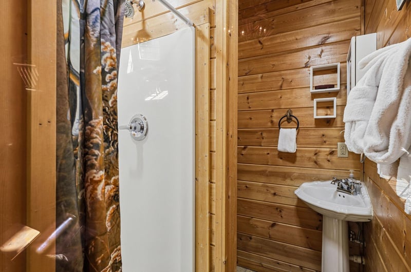 Step into your private rustic bathroom with modern amenities, featuring a refreshing shower and cozy log cabin charm.