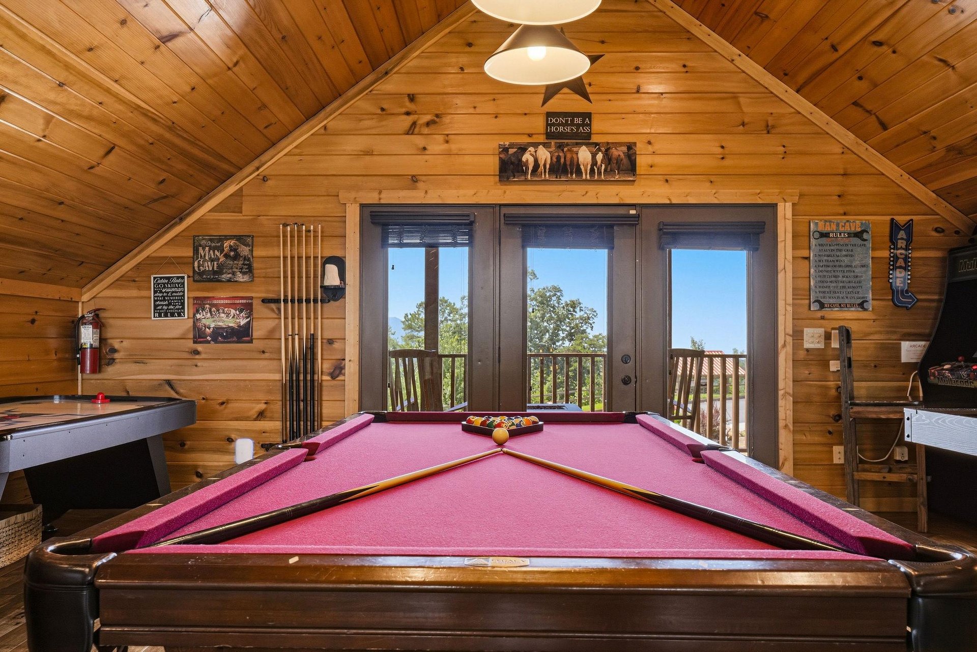 Challenge your crew to a game on the fullsized pool table in this inviting loft game room, where rustic charm meets playful competition under warm wood beams.