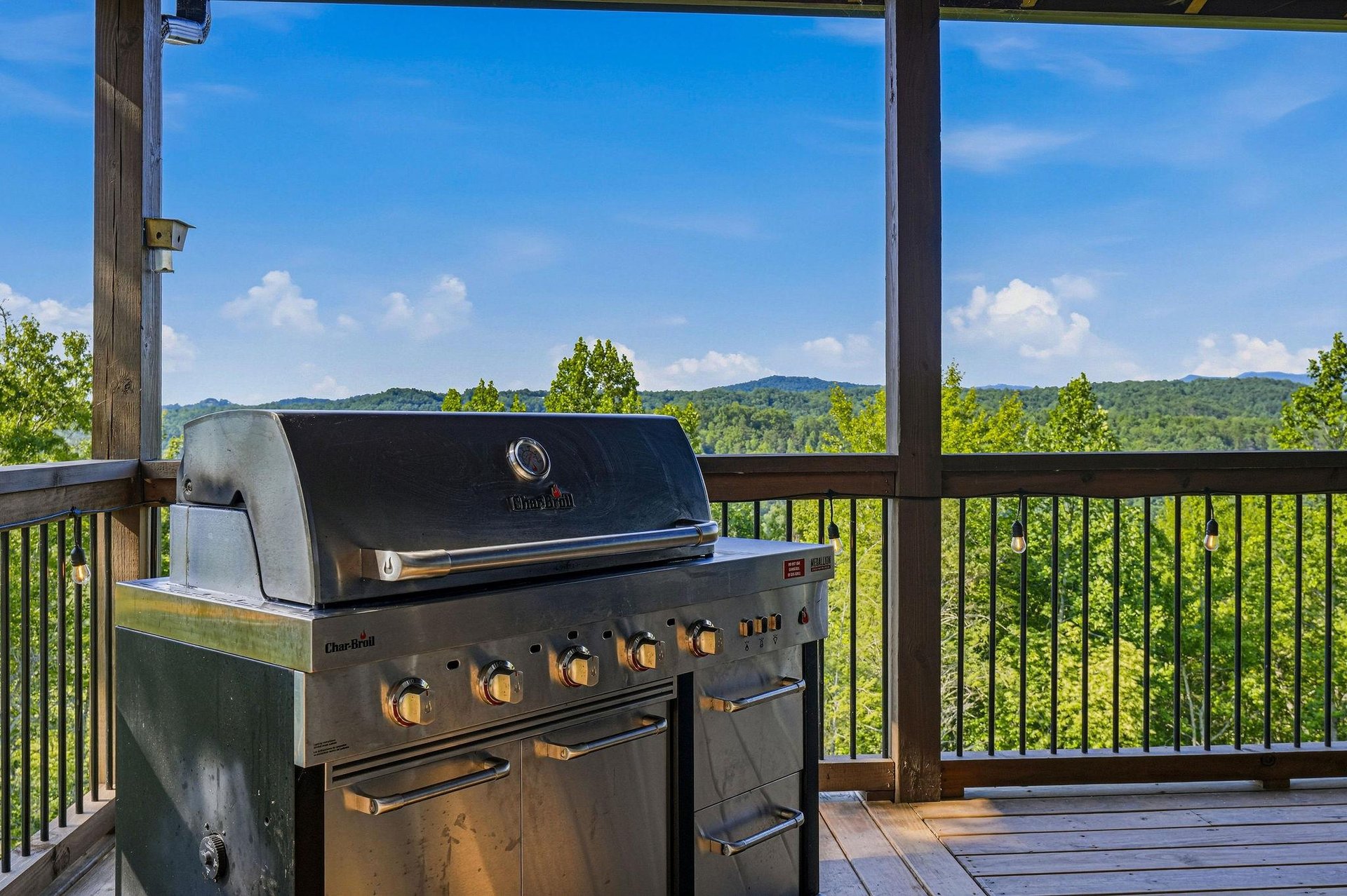 A covered deck with panoramic mountain views offers an ideal setting for outdoor grilling and al fresco dining in the surrounding hills.