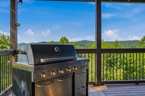 A covered deck with panoramic mountain views offers an ideal setting for outdoor grilling and al fresco dining in the surrounding hills.