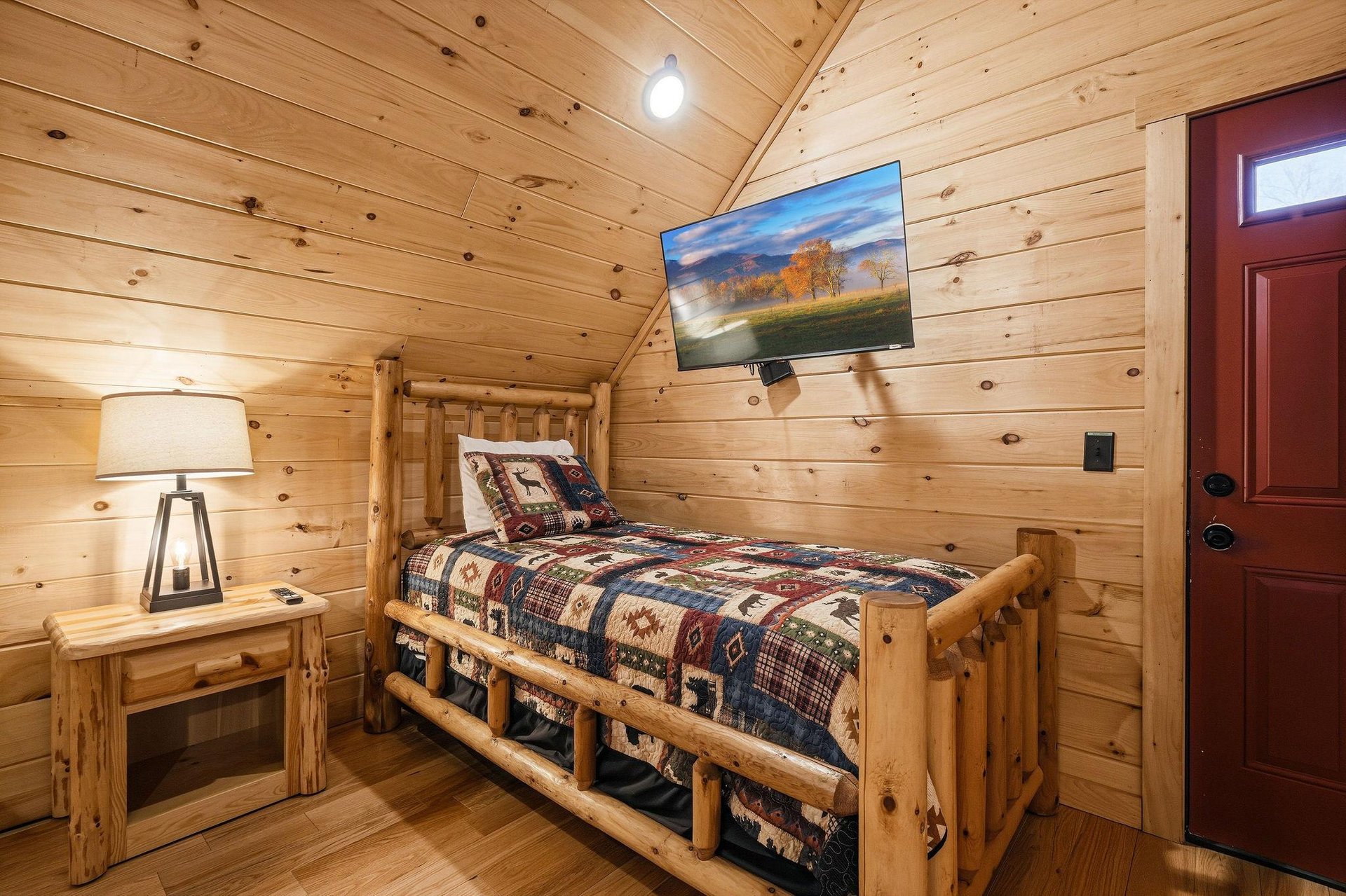 Cozy log cabin bedroom where youll drift off surrounded by warm wood walls and rustic charm, complete with your own TV for relaxing evenings.