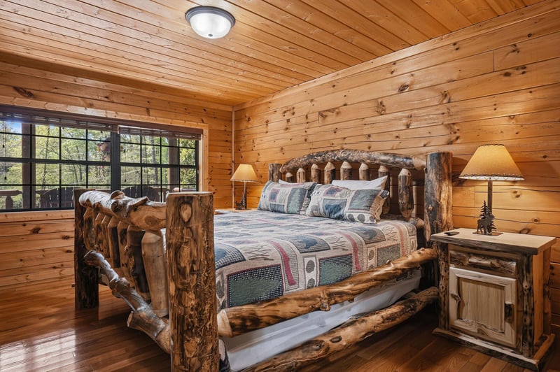 Your rustic log bedroom offers handcrafted wooden furniture and warm cabin charm, with natural light streaming through large windows for a peaceful mountain retreat.