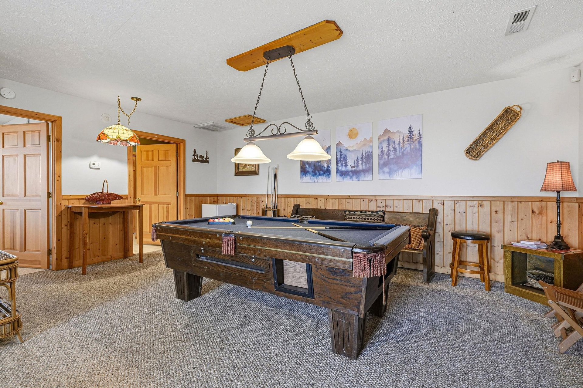 Challenge friends to a game of pool in your cozy recreation room, featuring rustic wood accents and mountain artwork.