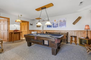 Challenge friends to a game of pool in your cozy recreation room, featuring rustic wood accents and mountain artwork.