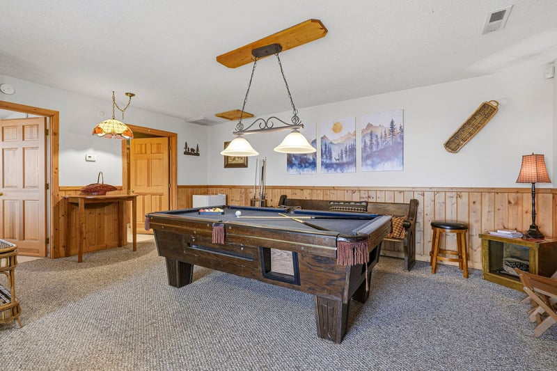 Challenge friends to a game of pool in your cozy recreation room, featuring rustic wood accents and mountain artwork.