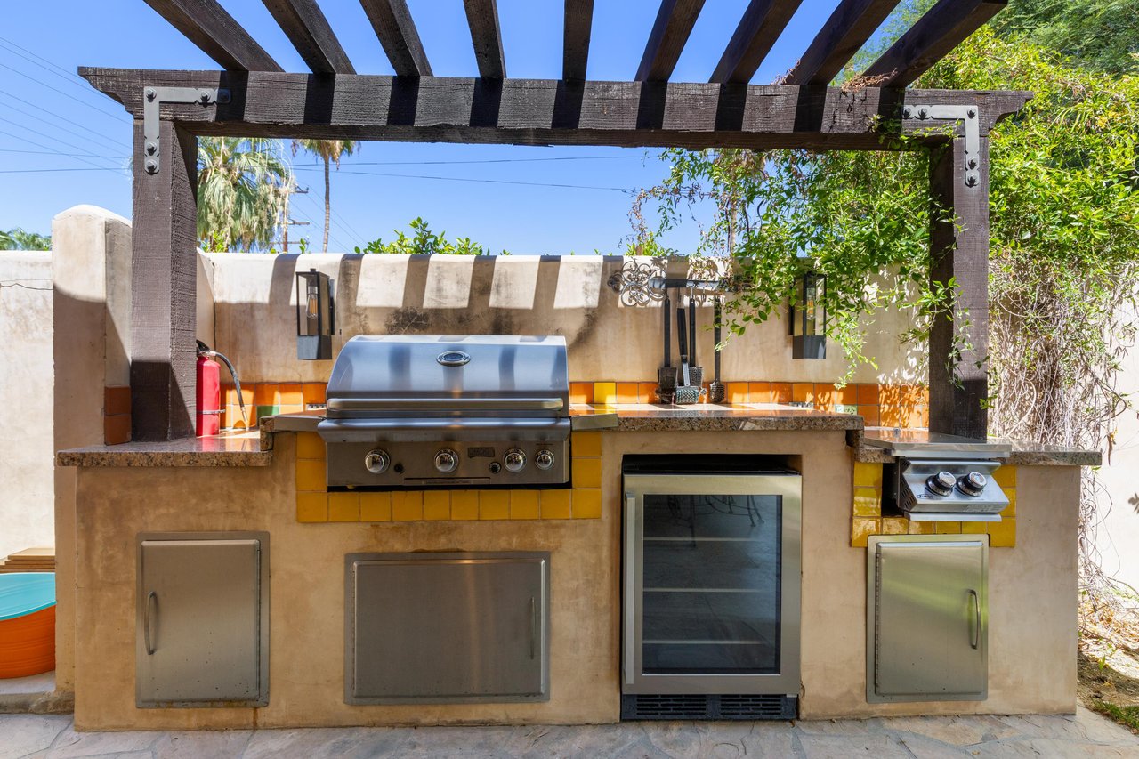 Outdoor kitchen with BBQ and mini fridge.