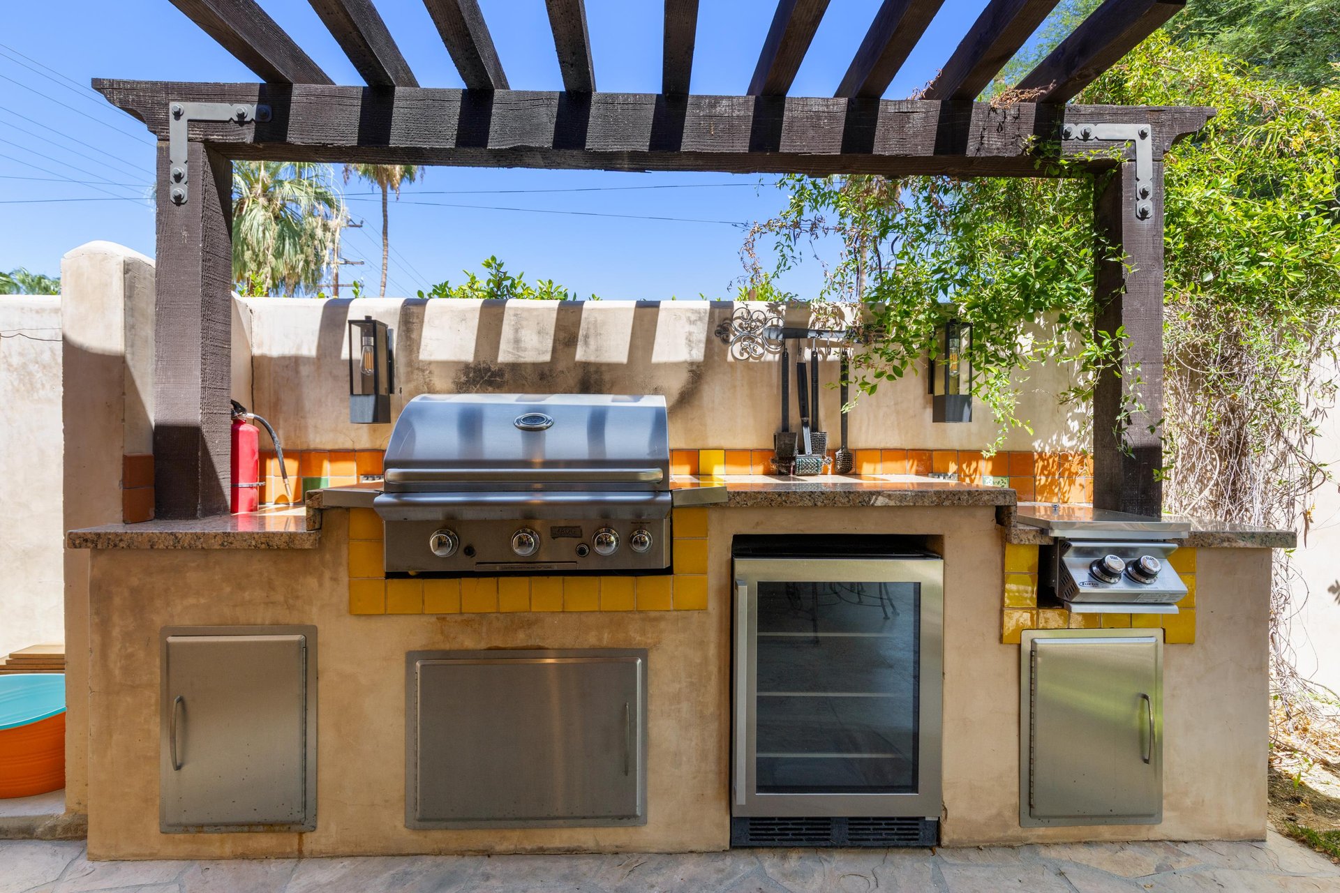 Outdoor kitchen with BBQ and mini fridge.