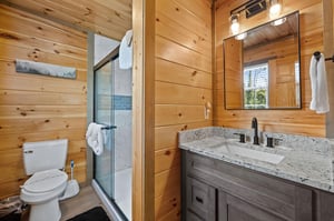 walk in tiled shower and a single vanity sink