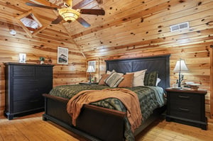 Unwind in your cozy cabin bedroom featuring rustic wood walls, plush bedding, and mountain charm that promises peaceful nights.
