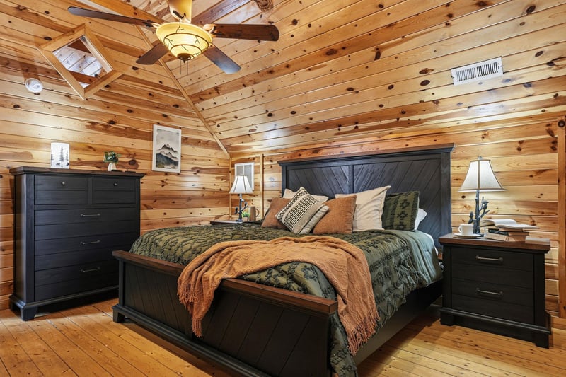 Unwind in your cozy cabin bedroom featuring rustic wood walls, plush bedding, and mountain charm that promises peaceful nights.