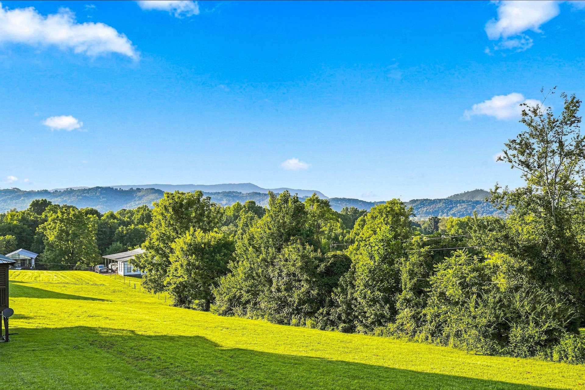 The property is set against a backdrop of rolling mountains and lush green countryside, offering a peaceful rural setting.