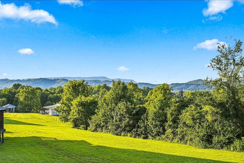 The property is set against a backdrop of rolling mountains and lush green countryside, offering a peaceful rural setting.