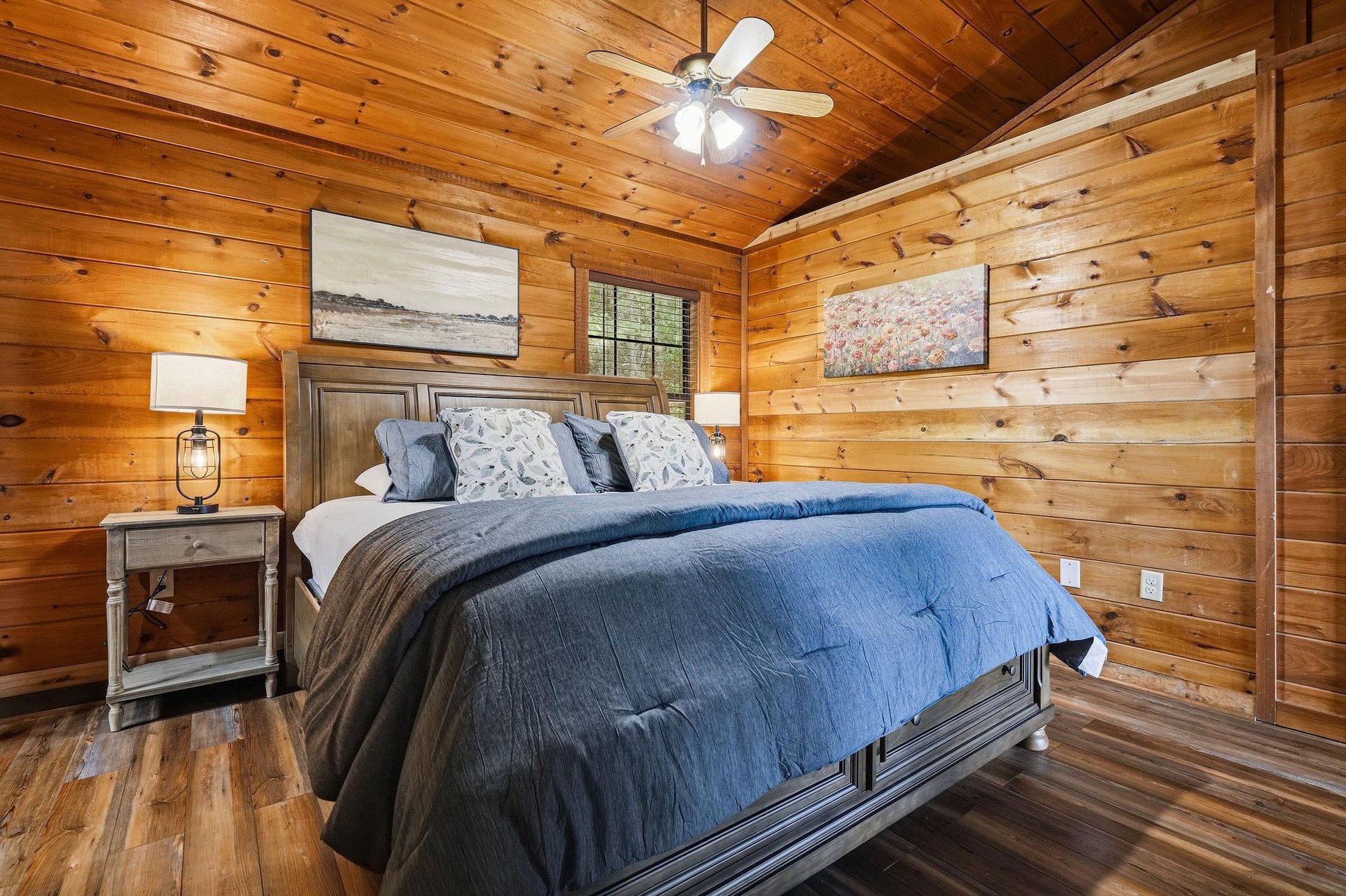 Sink into cozy comfort in this rustic bedroom with warm wood walls, soft bedding, and gentle lighting that creates the perfect retreat after your day of adventure.