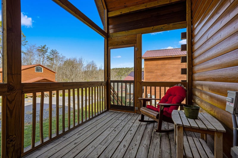 Unwind on your private covered porch with a cozy rocking chair and mountain views stretching beyond the peaceful cabin community.