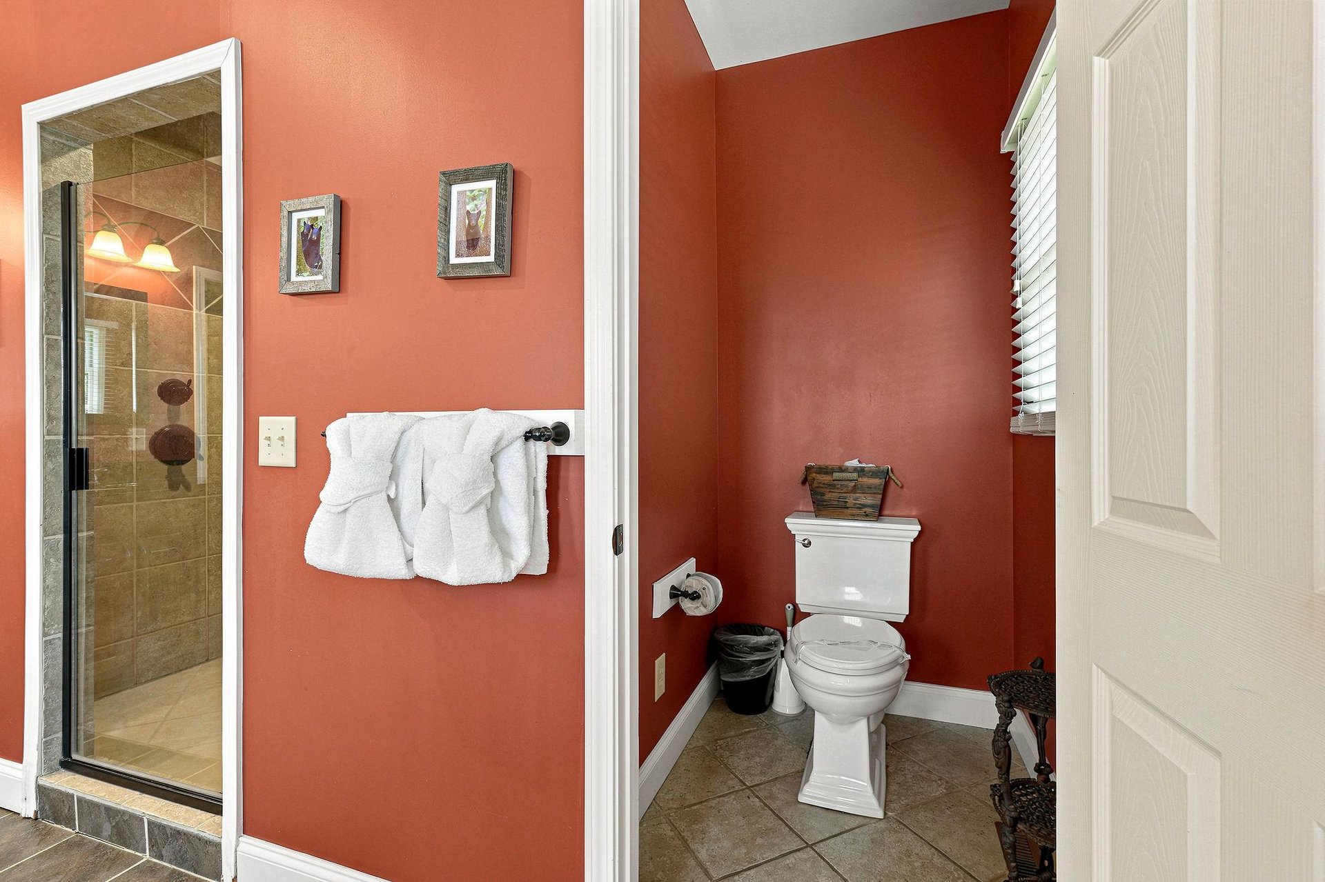 Step into your private bathroom, where warm coral walls and fresh towels invite you to unwind. The tiled shower and thoughtful décor create a cozy, welcoming retreat after a day of adventure.