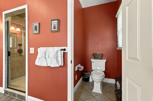 Step into your private bathroom, where warm coral walls and fresh towels invite you to unwind. The tiled shower and thoughtful décor create a cozy, welcoming retreat after a day of adventure.