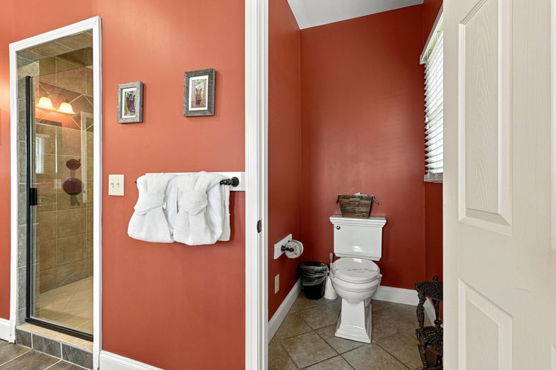 Step into your private bathroom, where warm coral walls and fresh towels invite you to unwind. The tiled shower and thoughtful décor create a cozy, welcoming retreat after a day of adventure.