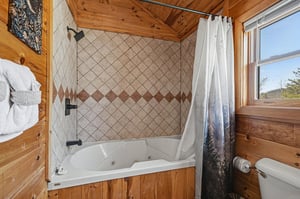 Soak in your private jetted tub surrounded by rustic wood walls and diamondpattern tile, with mountain views through the window.