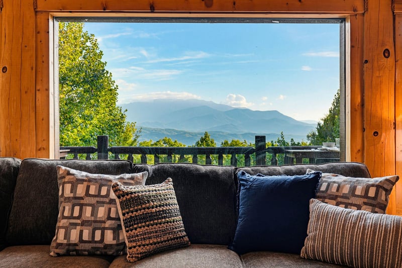 Cozy seating invites you to unwind in rustic warmth while majestic mountain vistas stretch out through the panoramic window.