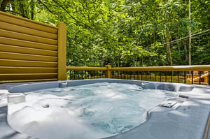 A private hot tub surrounded by lush forest greenery offers the perfect spot to unwind after your adventures, with the gentle sounds of nature all around you.