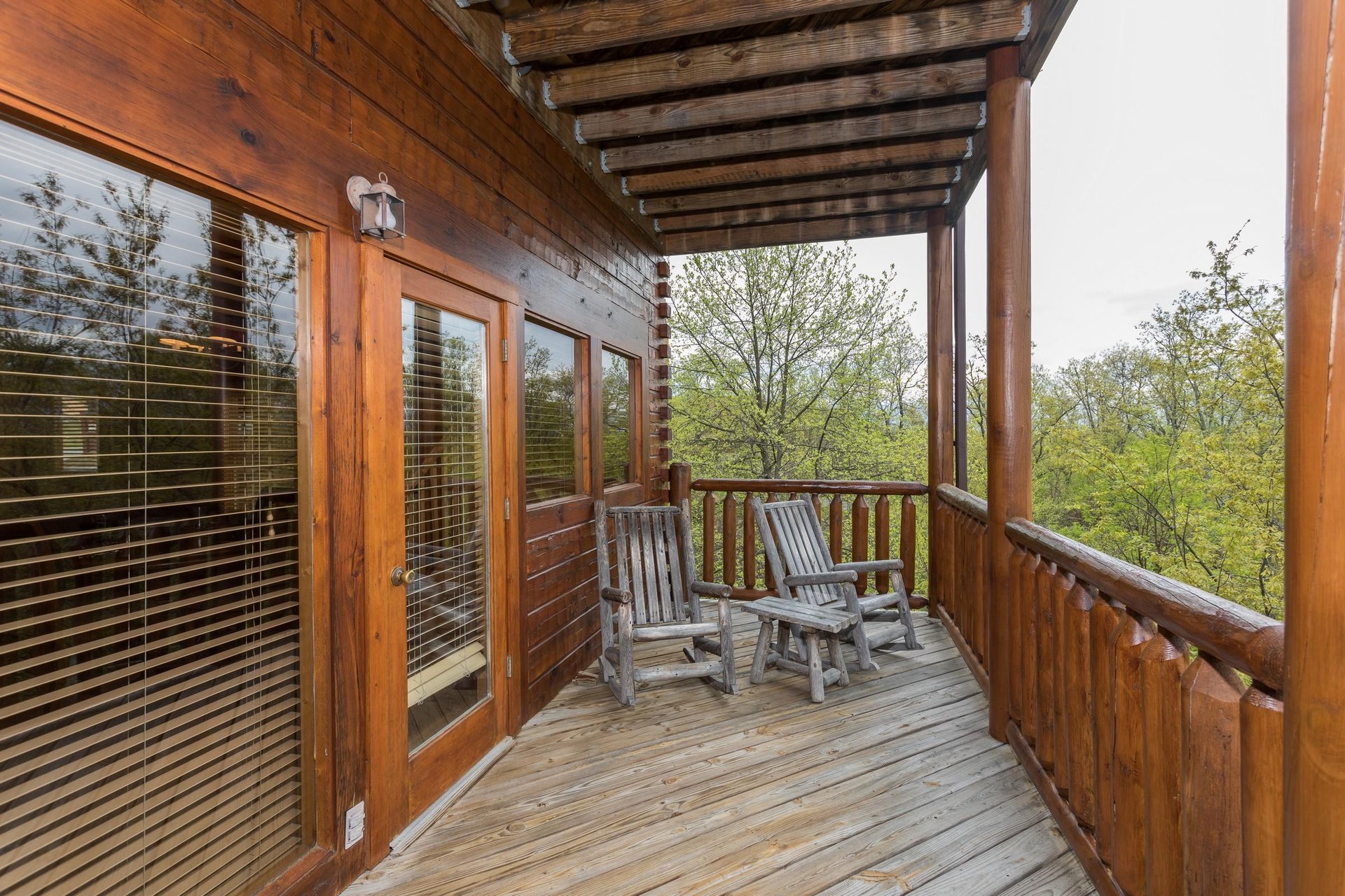 Two log rocking chairs on a covered deck at Howlin in the Smokies, a 2 bedroom cabin rental located in Pigeon Forge