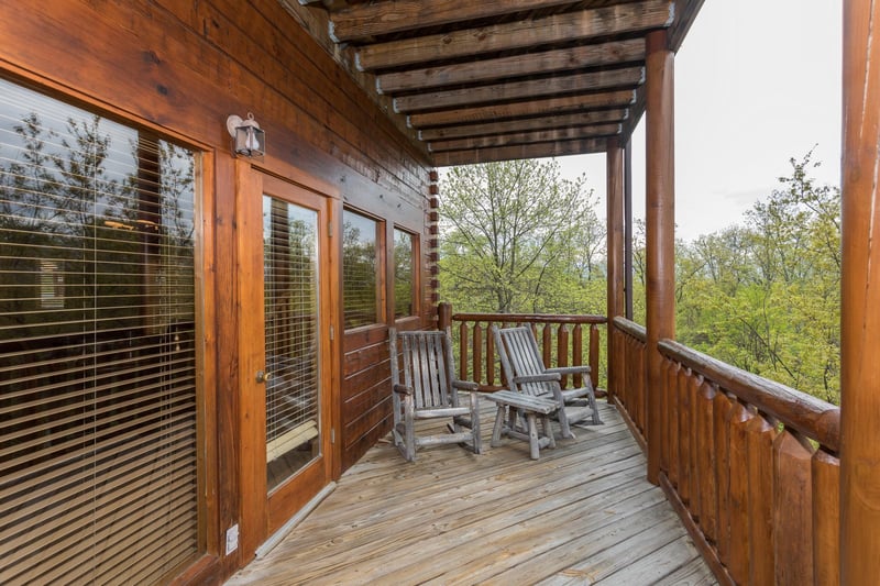 Two log rocking chairs on a covered deck at Howlin in the Smokies, a 2 bedroom cabin rental located in Pigeon Forge